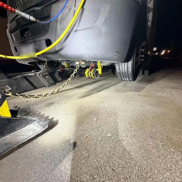 Semi truck front lifted on an underlift at night